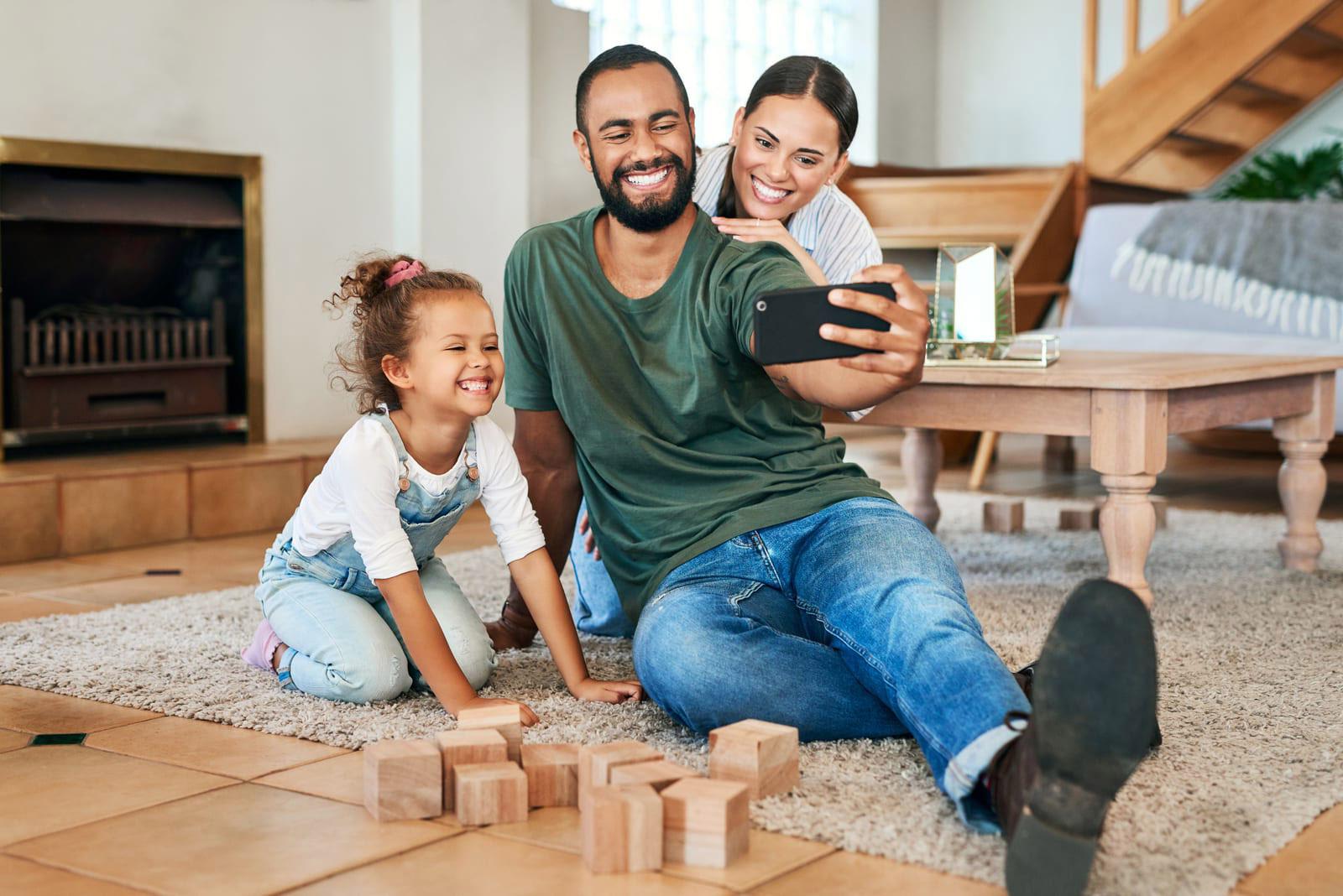 Familia sonriendo mientras se toma una selfie en casa